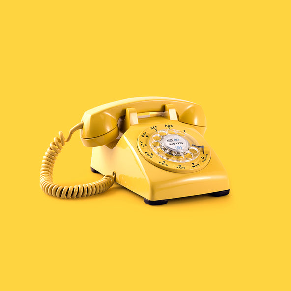 Old school yellow telephone on a bright yellow background